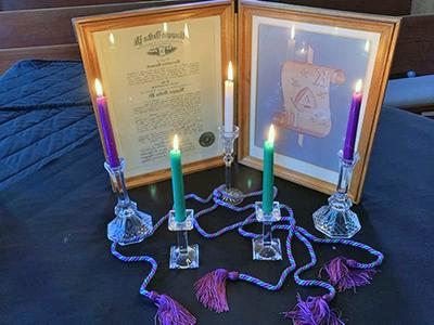 Burning candles in front of a framed honor society certificate